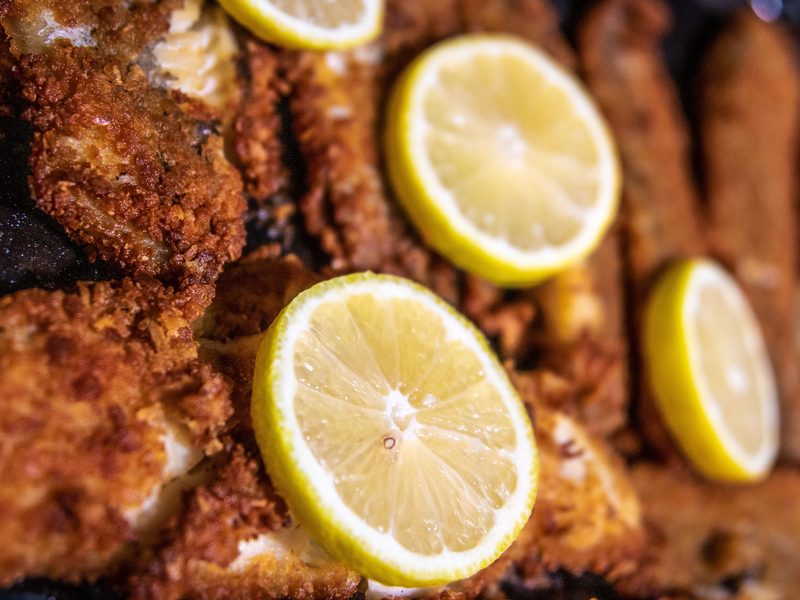 Crispy golden beer-battered white fish pieces served on a wire rack with fresh lemon wedges.