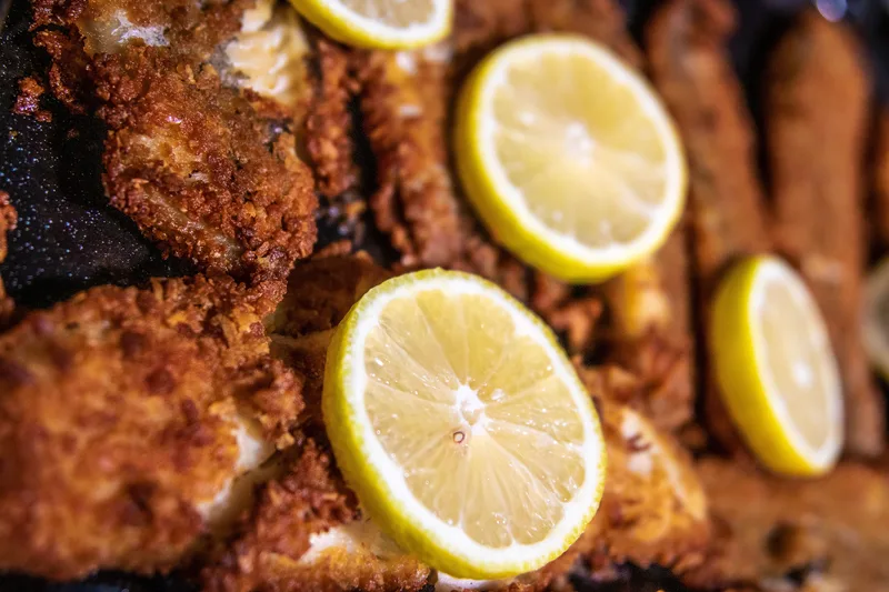 Crispy golden beer-battered white fish pieces served on a wire rack with fresh lemon wedges.